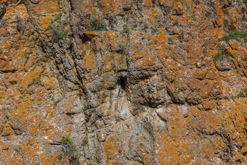 Rugged rock formation with orange lichen and crevice outdoors