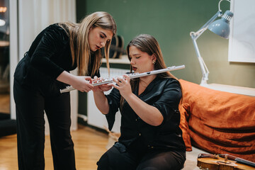 A teacher assists a student during a flute lesson, demonstrating the musical instrument's details....