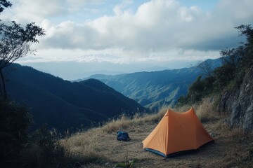 Camping in a serene mountain landscape with a vibrant orange tent under cloudy skies