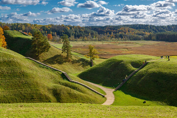 Calm autumn day in Kernave, Lithuania, featuring a walking trail and gentle hills in soft shades of brown and green