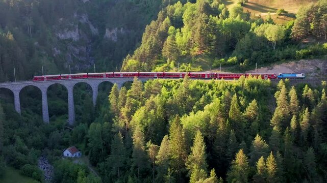  Passenger train crossing the Landwasser Viaduct in the Swiss Alps, red train on the railway. Unesco World Heritage, Red train on famous bridge.The Rhaetian Railway section from the Bernina area