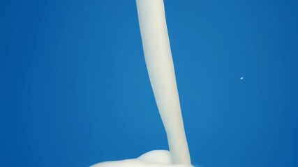 Fresh milk is poured, creating a beautiful crown splash on a vibrant blue studio background A clean, fresh concept for beverage or food advertising - Powered by Adobe