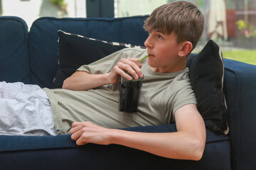 Teenage boy on a sofa with cola