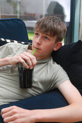 Teenage boy on a sofa with cola