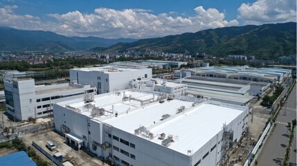 Aerial view of a large industrial complex under a blue sky with mountains. It can illustrate manufacturing, supply chain, and factory concepts.