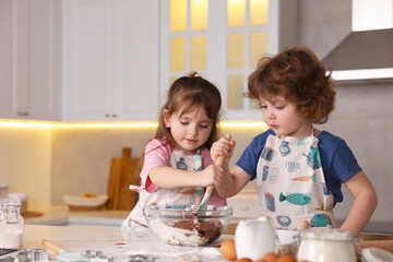 Cooking recipe. Cute children mixing dough for cookies at table in kitchen