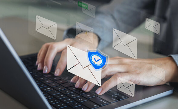 Closeup of hands typing on laptop with digital email icons and blue shield symbol representing secure encrypted communication and data protection technology