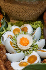 Halved salted duck eggs with vibrant orange yolks, arranged on lettuce and garnished with carved...