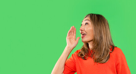 Woman shouting expression in bright orange shirt against a green background during a lively...