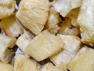 Fried cassava, golden yellow in color and crispy texture can be seen filling the entire frame, showing details of the fibers and soft inside