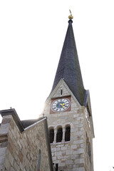 A stone church tower with a tall, dark pointed spire topped by a golden cross. The tower features a...
