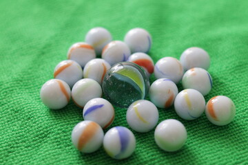 Una toma de cerca  de varias canicas o metras de diferentes tamaños sobre una tela de color verde