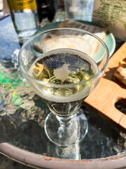 Glass of sparkling wine resting on glass table with appetizers in the background