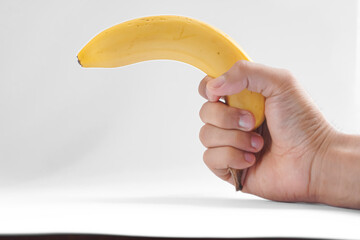 A hand holding a banana like a gun, against a plain white background.