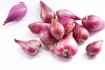 A cluster of small, vibrant pink shallots scattered on a white background.