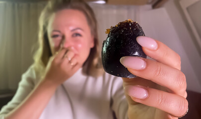 black spoiled egg in girl's hand. Girl plugged her nose with her fingers from bad smell