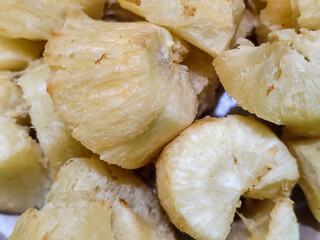 Fried cassava, golden yellow in color and crispy texture can be seen filling the entire frame, showing details of the fibers and soft inside