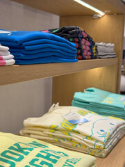 Stacked Graphic TShirts on Wooden Shelves. Vibrant Prints and Motivational Accent