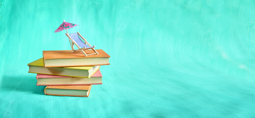 stack of books with deckchair and sun umbrella, spring and summer holiday read. Vacation,travel, inspiration,relaxation with books,reading and literature concept.