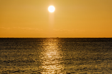 朝日が昇る海と黄金色に輝く水面