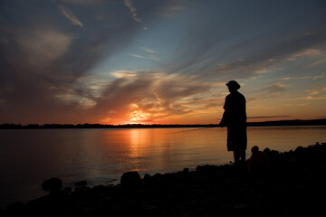 Fototapeta premium silhouette of man fishing at sunset
