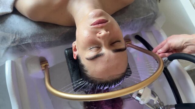 Close-up of a woman receiving a head massage during a Japanese head spa treatment with water flowing from a special hair washing tool, focusing on the scalp relaxation and beauty therapy	
