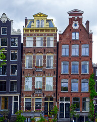 Fototapeta premium Row of colorful narrow dutch style houses with gables and large windows lining a canal in amsterdam, netherlands, europe