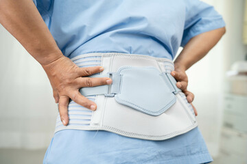 Asian woman patient wearing back pain support belt for orthopedic lumbar with walker.