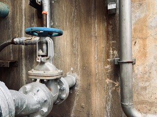 old gas pump. Industrial valve connected to a large storage tank with stainless steel piping in a...