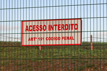 Access denied sign on fence at lisbon airport, warning of penal code article 191