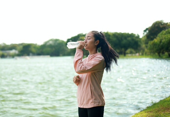 Thirsty girl drinking water Hot day Young woman Jogging Playing sports and living a healthy life...