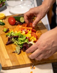 Hands Preparing Colorful Salad with Fresh Vegetables on Wooden Cutting Board. Healthy Meal Ingredients for Clean Eating. Vibrant Plant-Based Food Preparation