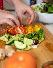 Hands Preparing Colorful Salad with Fresh Vegetables on Wooden Cutting Board. Healthy Meal Ingredients for Clean Eating. Vibrant Plant-Based Food Preparation