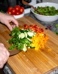 Hands Preparing Colorful Salad with Fresh Vegetables on Wooden Cutting Board. Healthy Meal Ingredients for Clean Eating. Vibrant Plant-Based Food Preparation