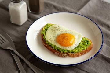 Homemade Avocado Toast with Egg on a Plate, side view. Close-up.