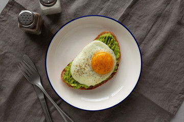 Homemade Avocado Toast with Egg on a Plate, top view.