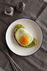 Homemade Avocado Toast with Egg on a Plate, top view.