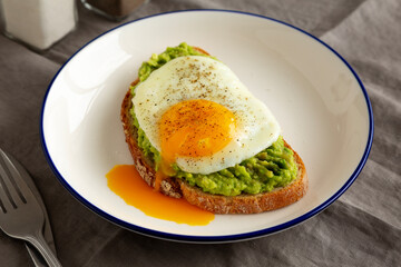 Homemade Avocado Toast with Egg on a Plate, side view. Close-up.