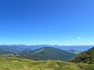 Scenic mountain landscape with green hills and vibrant blue sky.