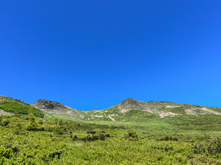 Green mountain landscape under a clear blue sky.