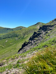 Lush green mountain landscape under a clear blue sky.