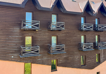 Wooden building facade with balconies and windows reflecting light.