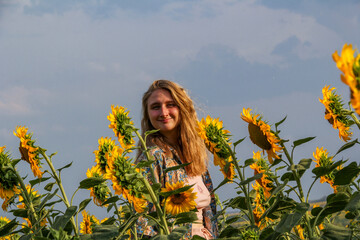 blonde woman in a field of yellow sunflowers, portrait, full face, looking into the lens, smiling,...