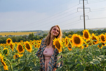 blonde woman in field of yellow sunflowers, waist-length portrait, full face, looking into lens,...