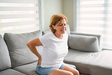 senior woman suffering from shoulder pain on sofa