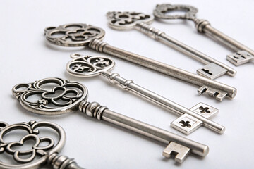 Antique decorative keys in row on neutral background. Set of six ornate antique-style keys with unique designs and metallic texture arranged in a row.