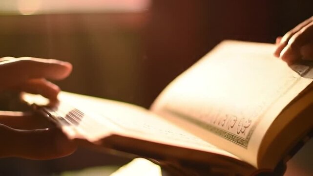 Illuminated manuscript. Person turning pages in vintage-toned light; script with ornate borders is featured on aged paper.