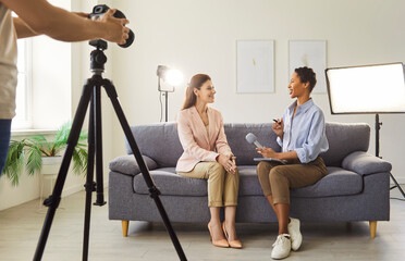 Professional digital camera recording live podcast video interview. Two young female bloggers...