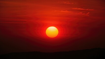 Fototapeta premium Glowing sun circle shining through a crimson evening backdrop. Sunset mood. Sky envelops the whole frame.