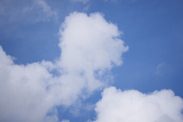 Obraz premium Bright blue sky with soft white clouds scattered across a clear day, evoking a sense of peace and natural freshness